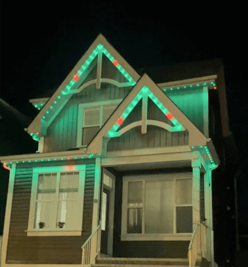 Green and red roofline lights on a house at night