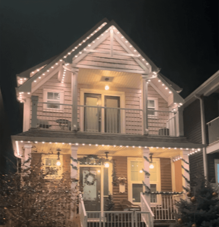 Permanent warm white roofline lighting on a two-story home at night