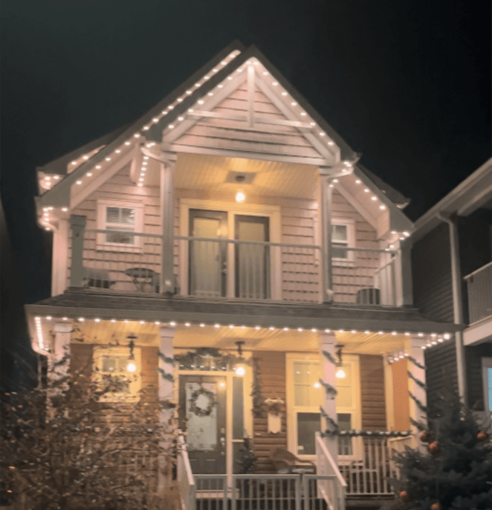 Warm exterior lights outlining the roof of a two-story home at night
